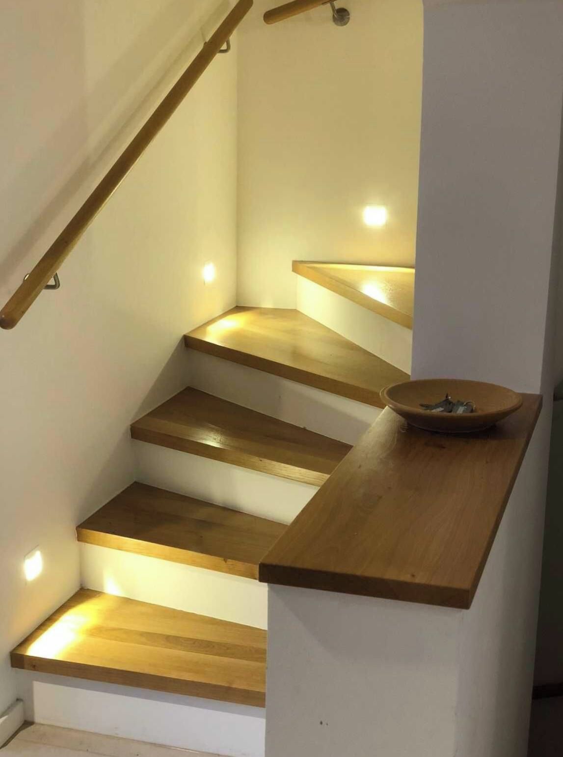 Una escalera con escalones de madera e iluminación empotrada.