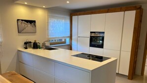 Una cocina moderna con una isla central, electrodomésticos integrados y un banco de madera.