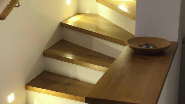 Una escalera con escalones de madera e iluminación integrada.