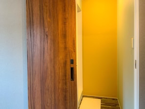A hallway with a wooden door, a yellow wall, and a white floor.