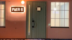 Ein Gebäude mit einer grünen Tür, einem Schild mit der Aufschrift 'PEER 6' und einem beleuchteten Fenster.