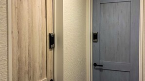 Zwei Holztüren mit modernen elektronischen Schlössern, eine davon neben einer strukturierten Wand.