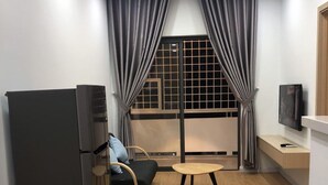 Ein kompakter Wohnraum mit Küchenzeile, einer Couch, einem kleinen Tisch und einem Fernseher.