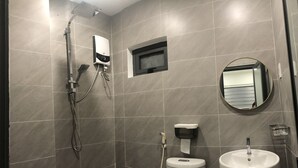 Ein modernes Badezimmer mit grauen Fliesen, einer Handbrause, einer Toilette, einem Waschbecken und einem Spiegel.