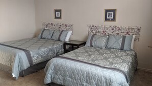 A bedroom with two beds, each with patterned bedding and headboards with floral designs.