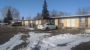 A building with a garage, a parked car, and snow on the ground.