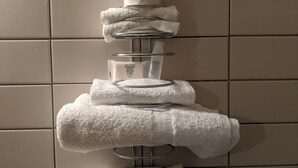 A bathroom with a towel rack holding several white towels.