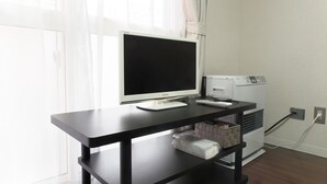Un escritorio con un monitor, teclado y control remoto.