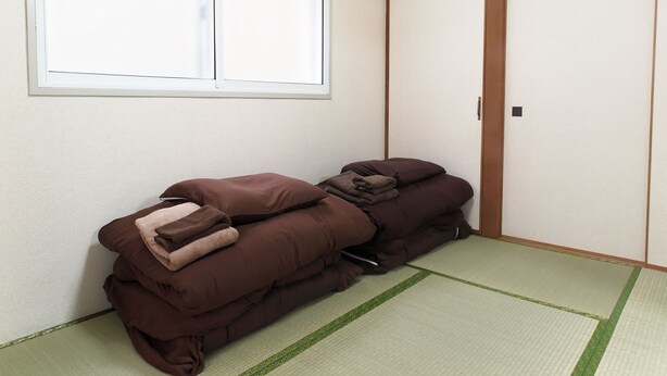 Una habitación con suelo de tatami, puertas correderas y una ventana con persianas.