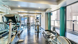 Una palestra con macchinari cardio, attrezzature per sollevamento pesi e uno specchio a parete.