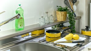 A kitchen with a stainless steel sink, a yellow pot, lemons, and a bottle of apple vinegar. - Heights Showa 207 (Sapporo)