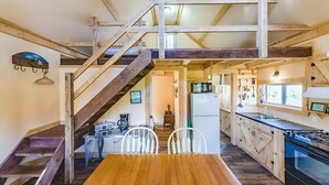 Una cocina rústica con vigas de madera, una mesa de comedor, sillas, un refrigerador y un microondas.