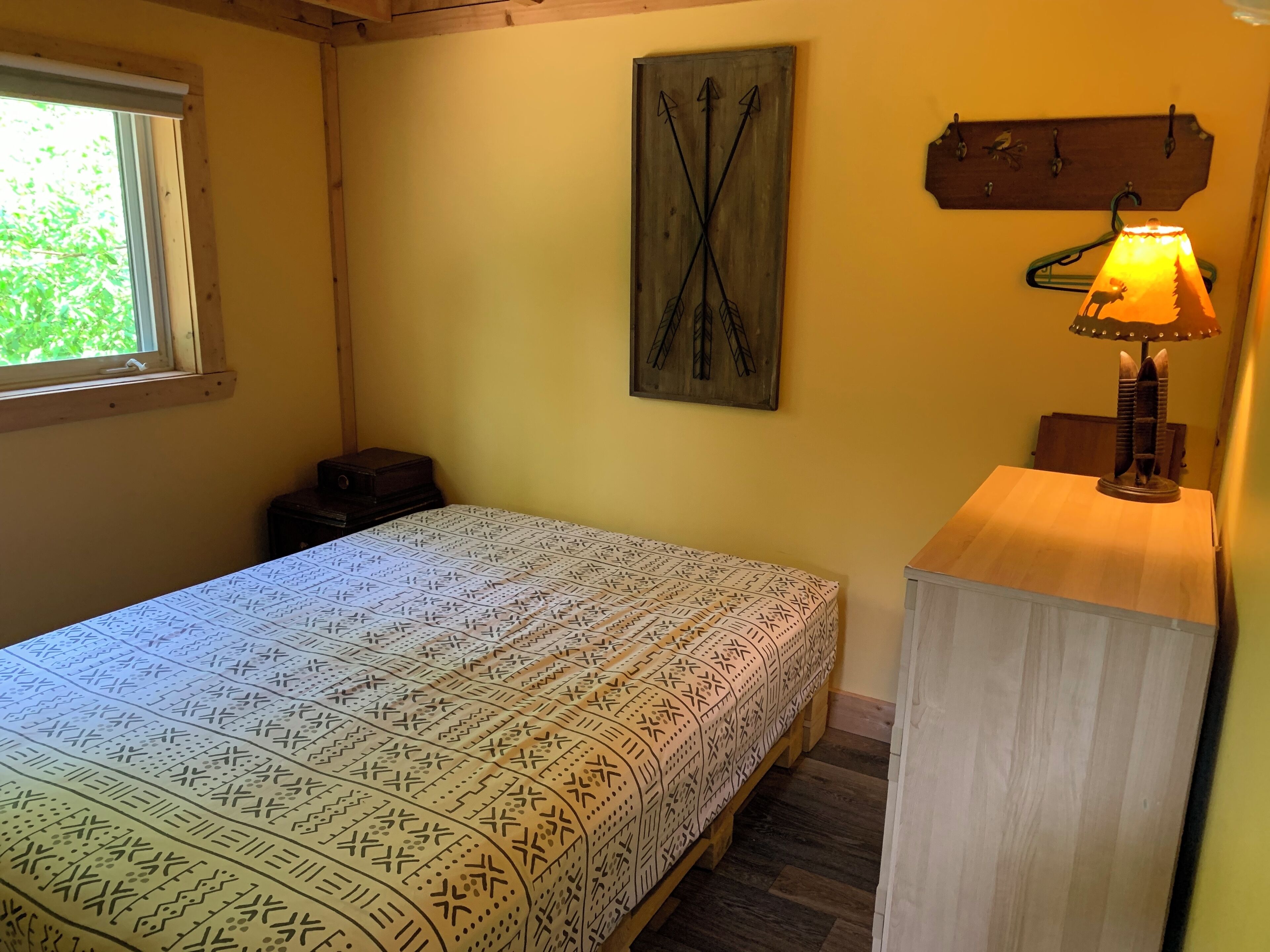 Un dormitorio pequeño y acogedor con cama, mesita de noche, lámpara de pared y ventana.