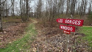 A signpost with directions to 'LES GORGES' and 'WINDIGO' in a wooded area.