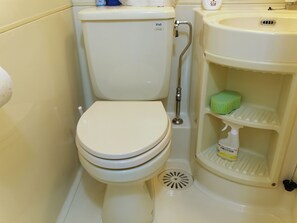 Inodoro con asiento bidé, repisa con una esponja y un cepillo de váter.