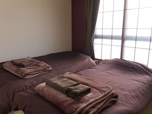 A room with two beds, each with a folded towel. - Heights Showa 208 (Sapporo)