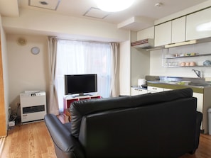 A compact hotel room with a flat-screen TV, a small kitchenette, a leather sofa, and a window with curtains. - Heights Showa 208 (Sapporo)