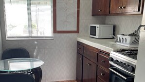 Una cocina con mesa, sillas, microondas, armarios y horno.