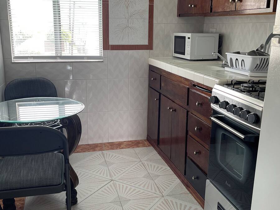 Une cuisine équipée d’une table à manger, de chaises, d’un four à micro-ondes, de placards et d’un four traditionnel.