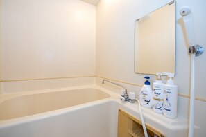 A bathroom with a bathtub, a mirror, and Dove toiletries. - Heights Showa 503 (Sapporo)