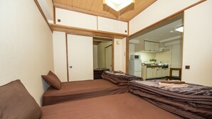 A room with two beds, a kitchenette, and a sliding door leading to another room. - Heights Showa 503 (Sapporo)