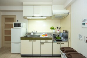 A compact kitchen with white cabinets, a microwave, a sink, and a stove.