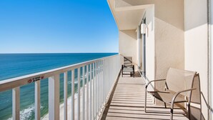 A balcony with a view of the ocean, a chair, and a railing with a no-smoking sign.