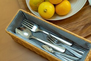Ein Korbtablett mit Löffel, Gabel und Messer auf einem Tisch.