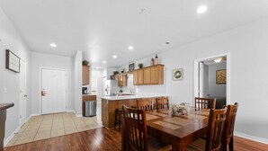 A modern kitchen with wooden cabinets, a central island, and a dining area with a wooden table and chairs. - Thousand Hills Golf View Condo Walkin w/ Elevator (Branson)