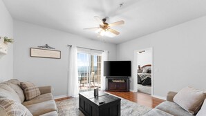 A spacious living room with a ceiling fan, a flat-screen TV, and a large window. - Thousand Hills Golf View Condo Walkin w/ Elevator (Branson)