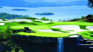 A golf course with sand bunkers, a waterfall, and a lake in the background. - Thousand Hills Golf View Condo Walkin w/ Elevator (Branson)