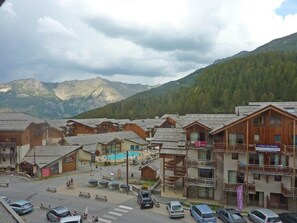A mountain resort with wooden buildings, a swimming pool, and a view of the mountains. - Apartment for 8 with pool in Les Orres (Les Orres)