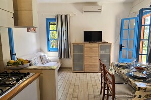 Kompakti keittiö, jossa on ruokailutila, sohva, televisio ja sininen ovi.