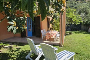 A patio with a table and chairs, a blue door, and a tree with yellow fruits. - Ground floor, 5 places (Costa Rei)