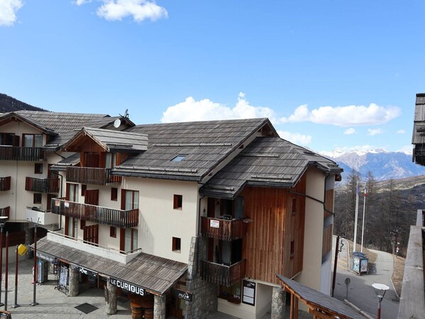 A traditional chalet-style building with balconies, a wooden facade, and a mountain backdrop.
