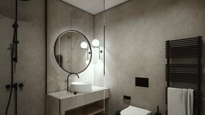 Un baño moderno con un espejo redondo, un lavabo blanco y un perchero para toallas.