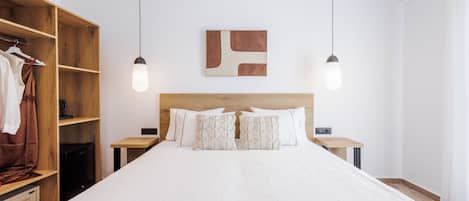A bedroom with a large bed, wooden wardrobe, bedside tables, and a wall-mounted abstract art piece.