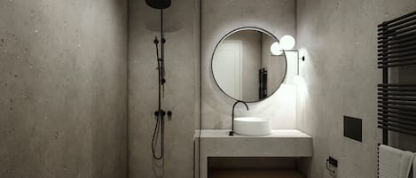 Een moderne badkamer met een vrijstaand wastafelmeubel, een ronde spiegel met verlichting, een toilet en een douche.