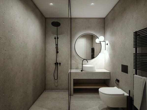A modern bathroom with a freestanding sink, a round mirror with lights, a toilet, and a shower. - Inoe Hotel (Santorini)
