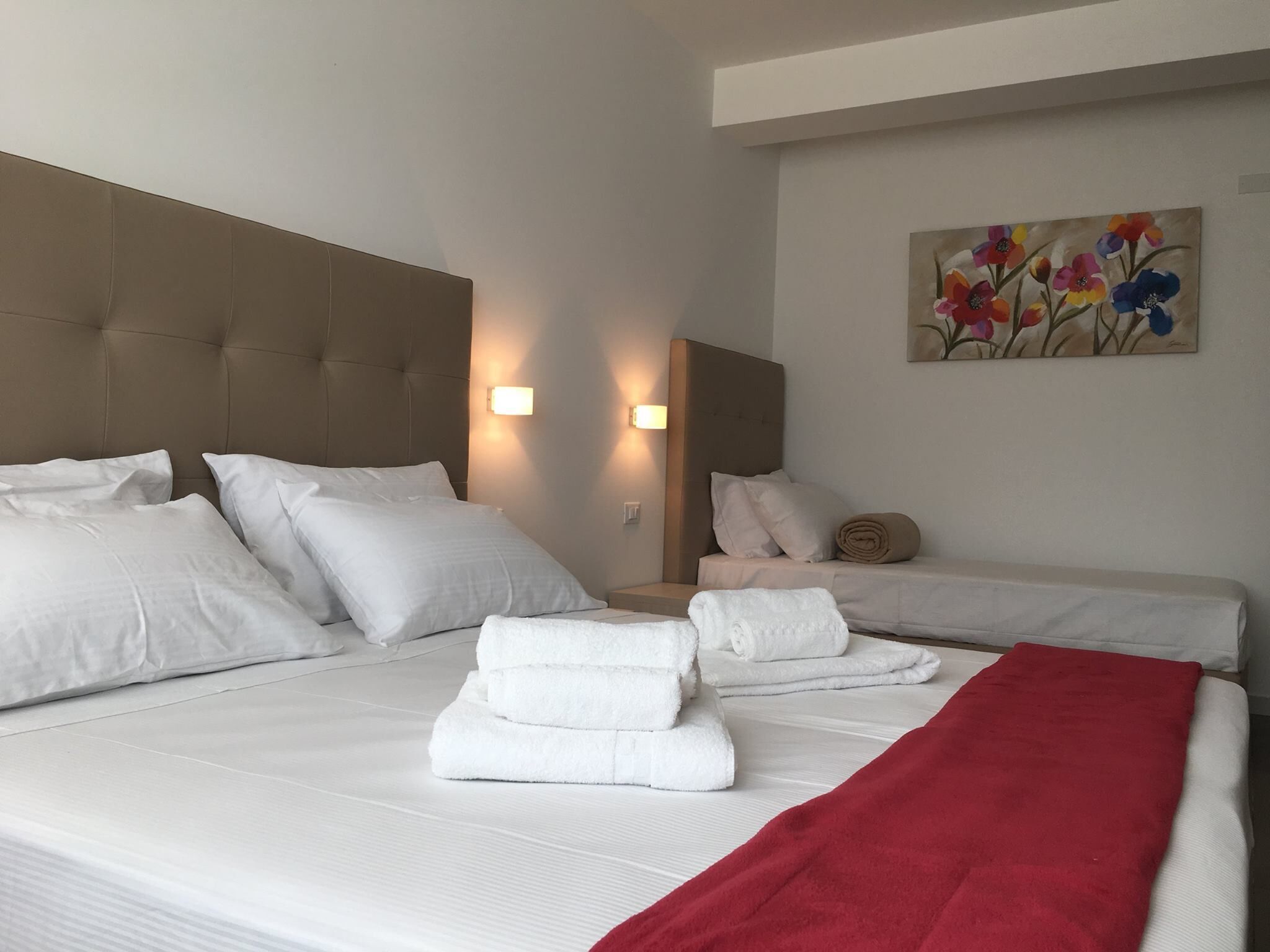 Una camera d'albergo con un letto grande, due comodini e un quadro appeso al muro.