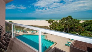 A balcony with a view of a beach, a pool, and lounge chairs. - Crescent Beach Club 3B Beachfront Views of the Gulf (Clearwater Beach)