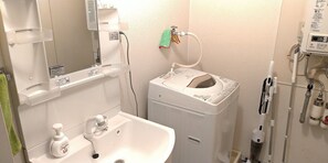 A bathroom with a sink, mirror, and a small white machine, possibly a hairdryer or heater.