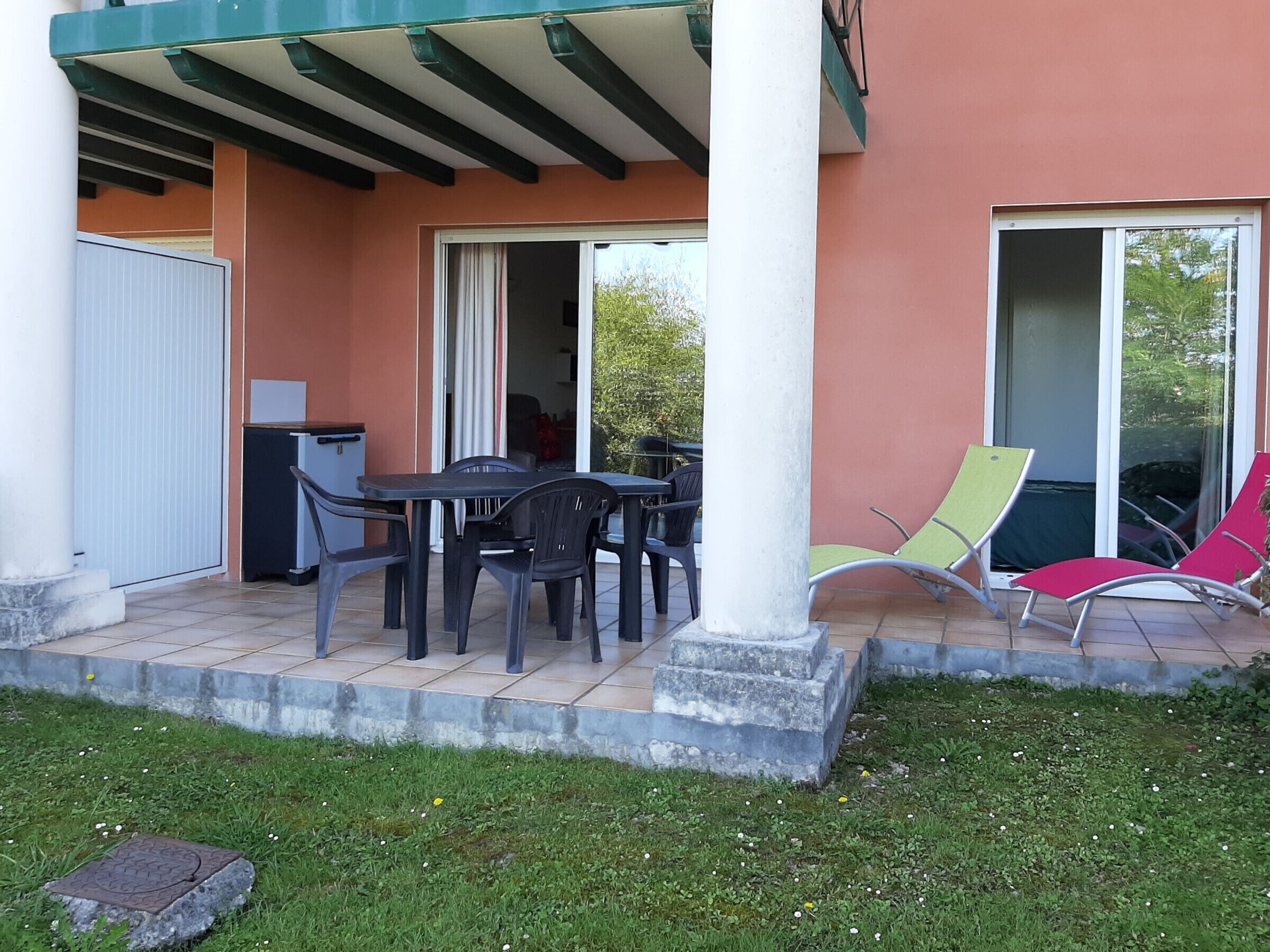 An outdoor patio with a table and chairs, a covered area, and a sliding glass door leading to a balcony.