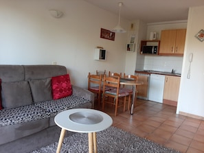 A living room with a grey sofa, a small round table, and a dining area with wooden chairs. - 2-Bedroom Apartment in Socoa near Beach with Terrace (Ciboure)