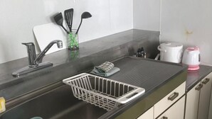 A kitchen with a stainless steel sink, a dish rack, a kettle, and a coffee maker. - Heights Showa 703 (Sapporo)