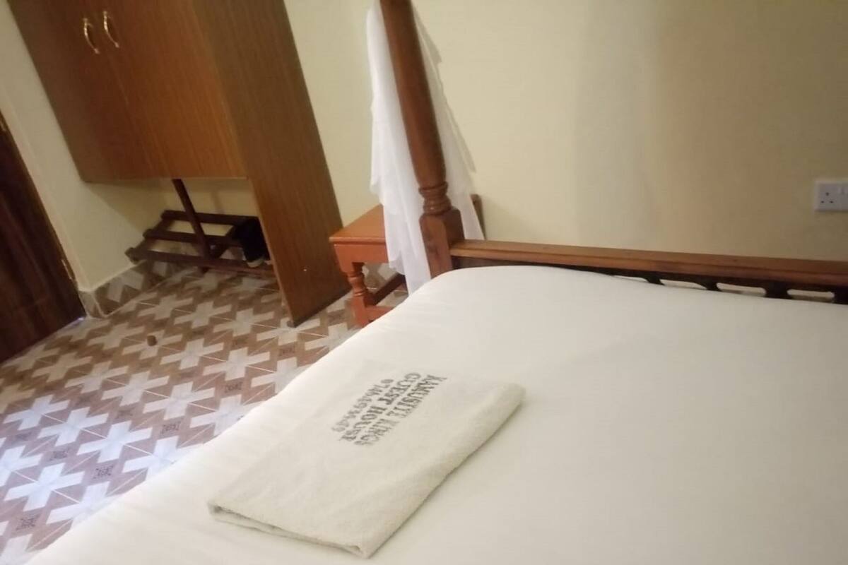 Una cama bien hecha con una toalla blanca doblada encima.