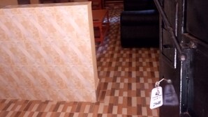 Una habitación con piso a cuadros, un sofá negro, un mueble de madera y una pared con diseño.