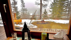 Een houten bureau met uitzicht op een besneeuwd landschap, een lantaarn, een glas en een groene doos.
