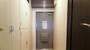 Ein Flur mit einer Tür am Ende, einem Lichtschalter und einem Thermostat an der Wand.