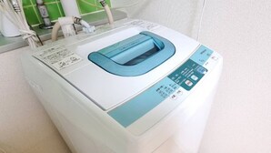 Eine Waschmaschine, vorne betrachtet, weiß mit einem blauen Bedienfeld und einer transparenten Tür.